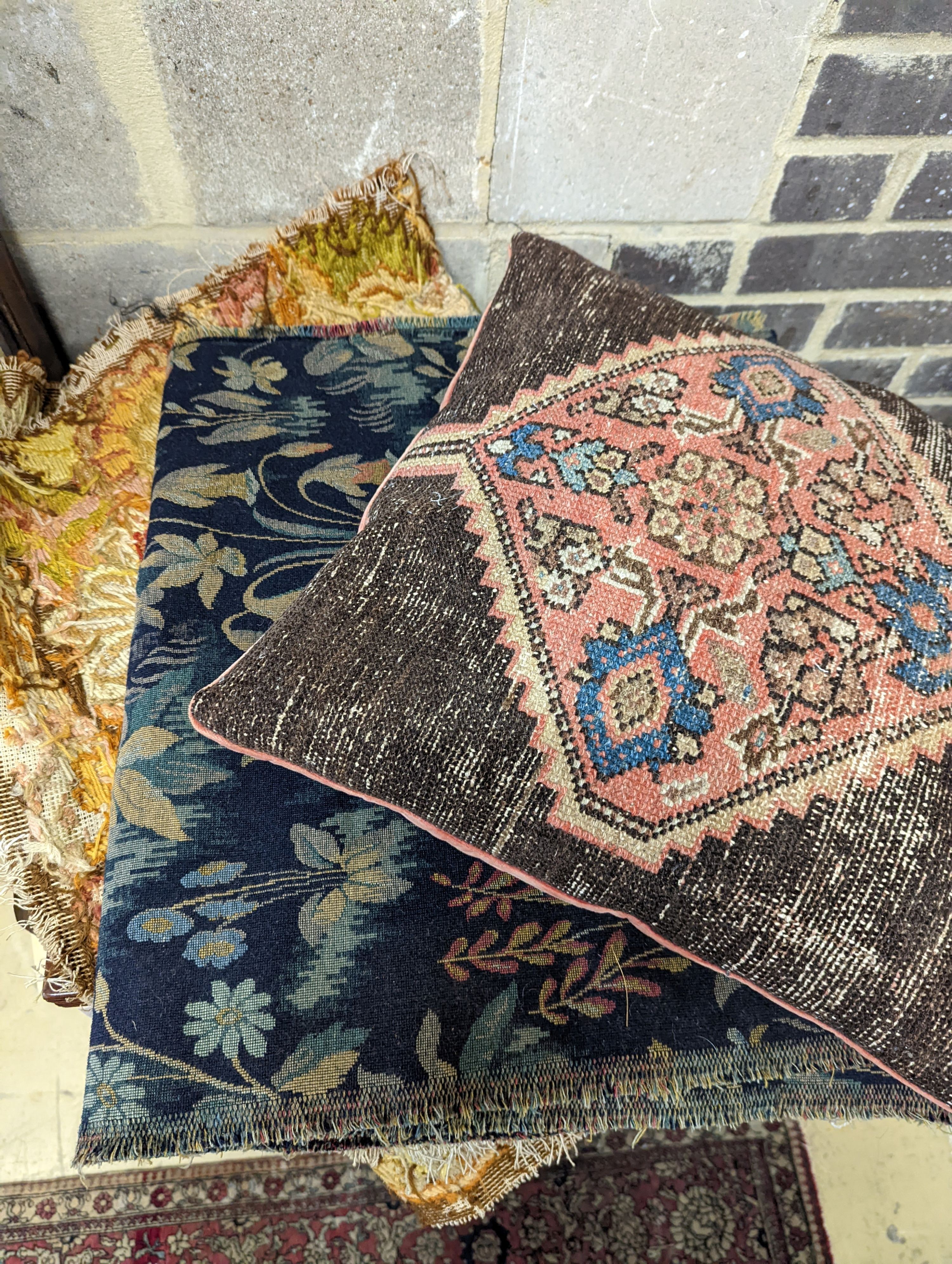 A length of machine tapestry fabric with flowers on a black ground, 420 x 52cm together with a Caucasian rug faced cushion and an antique English needlework panel with stylised scrolls 175 x 67cm